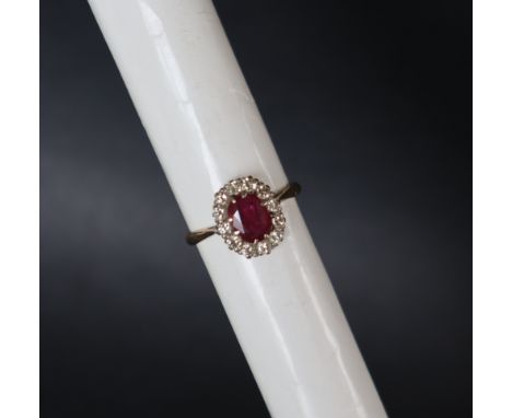 A ruby and diamond ring, the central oval faceted ruby approximately 8mm x 6mm surrounded by twelve round old cut diamonds to