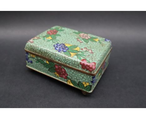 A Japanese cloisonne enamel box and cover of rectangular form decorated with flowers and leaves to a green ground, 10cm wide