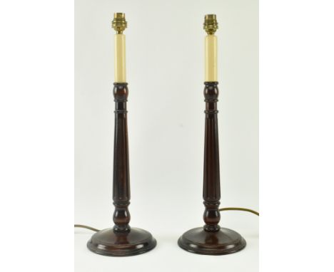 A pair of contemporary neo-classical inspired carved wood column desk table lamps. Each light having a faux candle shaped top