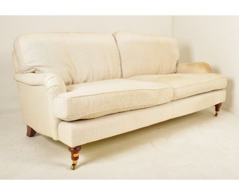 A Victorian inspired 20th century upholstered three seater sofa in the manner of Howard &amp; Sons. The sofa having a straigh