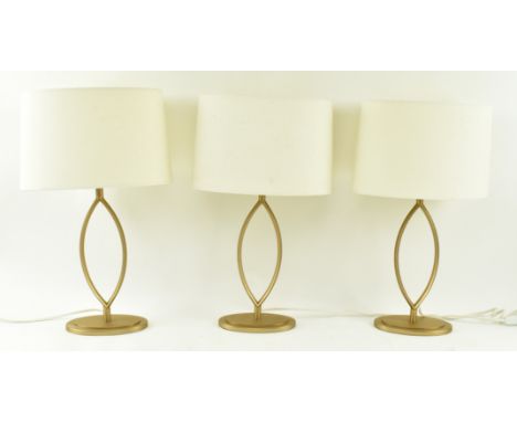 A set of three Contemporary high end design chrome gold metal desk table lamps. Each light having an oval ream fabric shade o