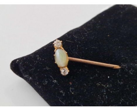 A gold stick pin with white and green stone terminal