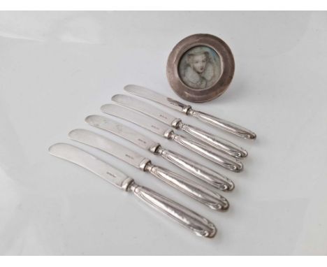 Set of six silver handled tea knives and a circular photo frame. 3 in diam.