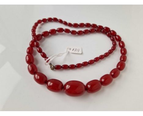 A STRING OF CHERRY AMBER BEADS 28 INCH 54 GMS