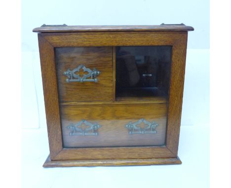 An oak smokers cabinet with bevelled glass door, with three pipe bowls, no tobacco jar 