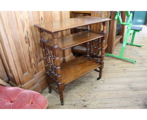 An Edwardian three tier book trolley with bobbin turned ends on castors