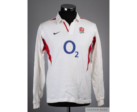 White and red England rugby shirt, the reverse bearing numerous player autographs, including Johnson, Catt, Borthwick, Tindal