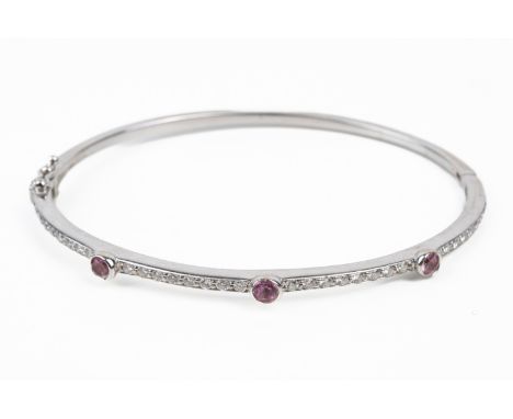 A PINK SAPPHIRE AND DIAMOND BANGLEThe top half of the bangle set with round brilliant cut diamonds and three bezel set round 