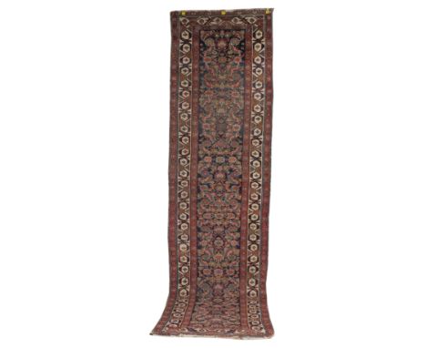 A FERAGHAN RUNNER, PERSIANThe indigo field with an allover herate design; an ivory bold vine and single flower border, 352 x 