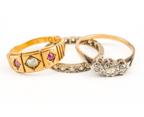 A VICTORIAN 15CT GOLD, RUBY AND HALF PEARL THREE STONE RING AND TWO FURTHER RINGS (3)The Victorian ring mounted with two cush