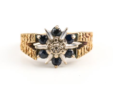 AN 18CT GOLD, SAPPHIRE AND DIAMOND SEVEN STONE CLUSTER RINGMounted with a single cut diamond at the centre, in a surround of 
