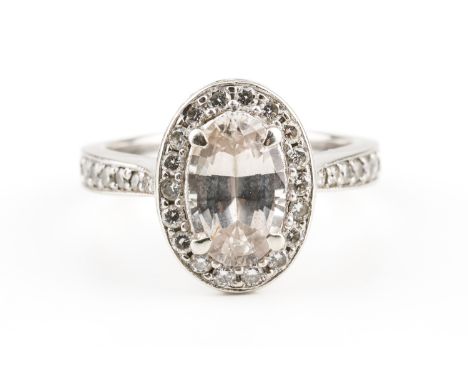 A SAPPHIRE AND DIAMOND RINGWith a central near colourless oval cut sapphire, claw set with a surround of round brilliant diam