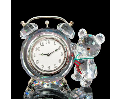 Clear crystal clock with rhodium alarm features and feet. Bear has clear crystal body, amber eyes and plaid bow. Swarovski ba