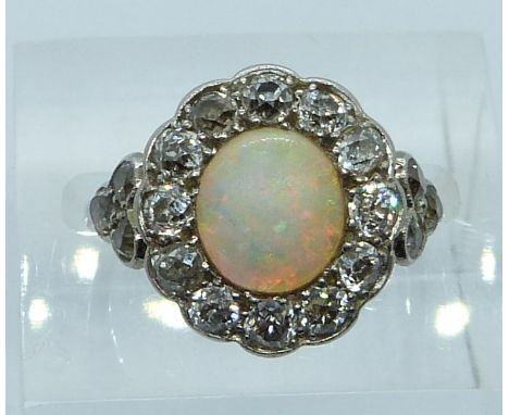 An 18ct white gold ring set with an oval opal cabochon surrounded by old cut diamonds, 3.6g, size L/M