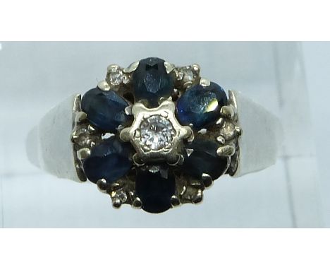 A 9ct white gold ring set with a diamond to the centre surrounded by sapphires, 3.6g, size Q