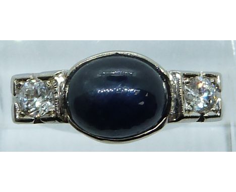 A 14k white gold ring set with a sapphire cabochon of approximately 2.1ct and two diamonds each approximately 0.2ct, 5.8g, si