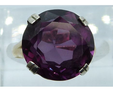 An 18ct gold ring set with a round cut synthetic purple sapphire, 4.3g, size I