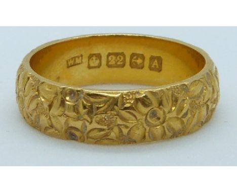 A 22ct gold wedding band with relief moulded flower decoration, Birmingham 1925, maker WM, 9g, size Q/R&nbsp;