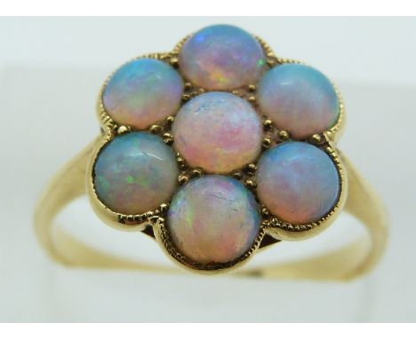 An 18ct gold ring set with seven round opal cabochons in a cluster, 3.8g, size O