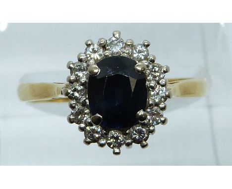 An 18ct gold ring set with an oval cut sapphire surrounded by diamonds, 3.9g, size Q