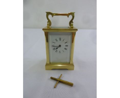 Brass carriage clock of customary form with enamel dial, Roman numerals, to include key