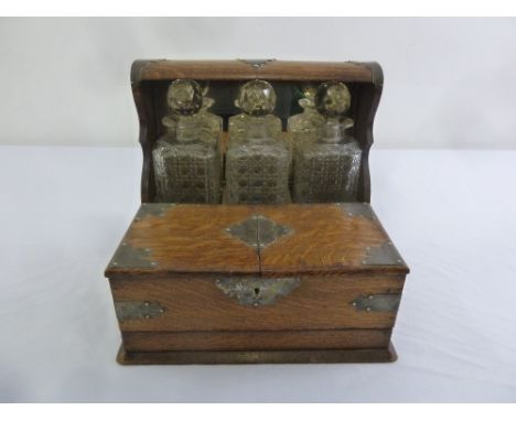 An oak cased three bottle Tantalus with attached cigar box and hallmarked silver mounts