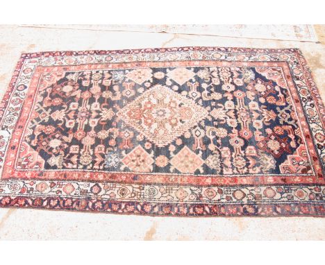 A Persian carpet decorated stylised flowers and central lozenge medallion on a dark blue ground with three border stripes, 80