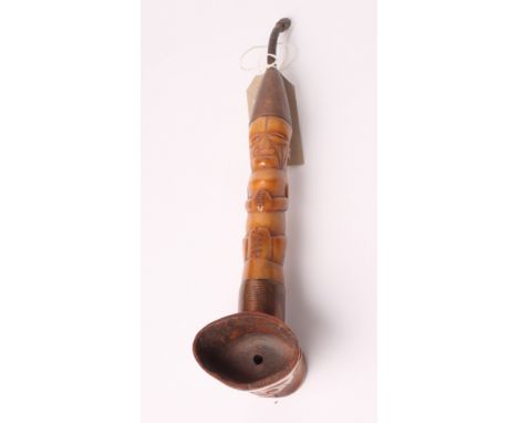 A tribal carved bone pipe of figural form with copper wire decoration