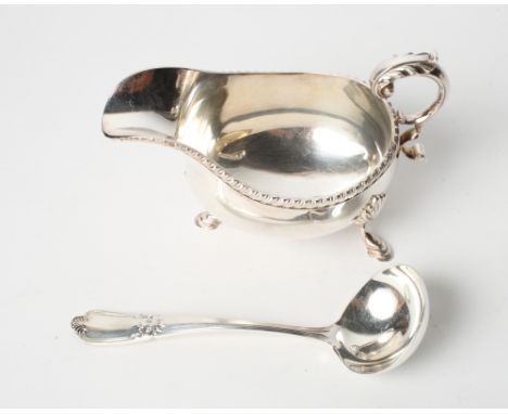 A silver sauce boat with gadrooned border and scrolled handle on three hoof feet and a matching sauce ladle, 12oz troy approx