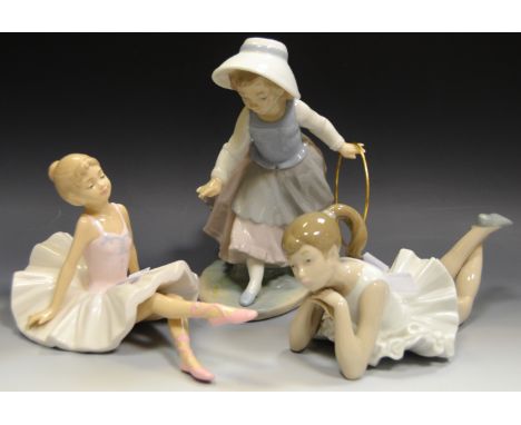 A Nao figure of a Ballerina; a Leonardo Collection figure of a seated Ballerina; a Nao figure of a Girl playing Hoop (3)