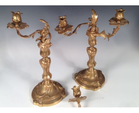 A pair of Rococo style gilt brass twin-light candelabra, late 19th century, each with a foliate cast stem and two arms with s