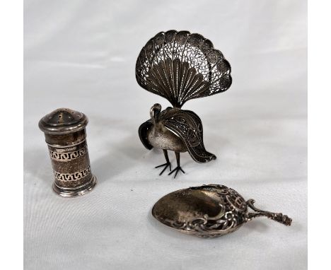 A silver caddy type spoon with import marks, a silver pepper pot, a white metal filigree peacock, stamped 925 and a white met