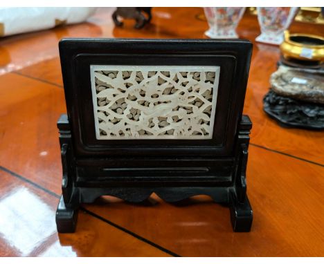 A Chinese jade coloured reticulated carved and pierced panel with dragons above and scrolling decoration below in table scree