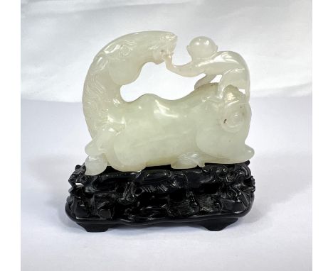 A Chinese carved jade group depicting monkey sat on top of a reclining horse on carved hardwood stand, length 6cm.