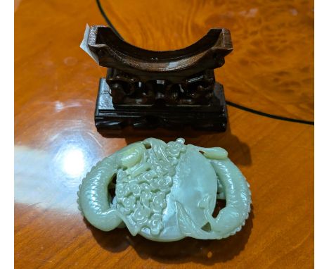 A Chinese jade coloured carving of dragons around the moon, on pierced hardwood stand, width 10cm.
