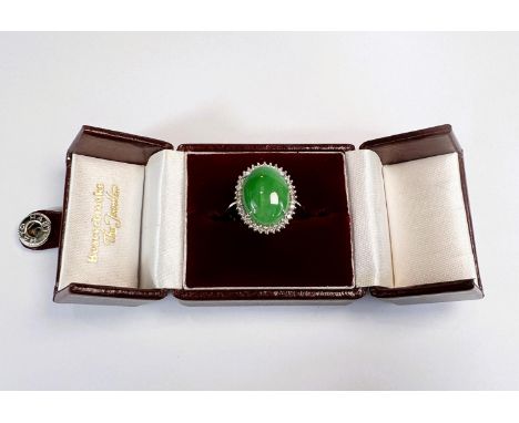 A jadeite and diamond dress ring, the central oval cabochon jadeite stone approx.&nbsp; &nbsp; surrounded by a band of brilli