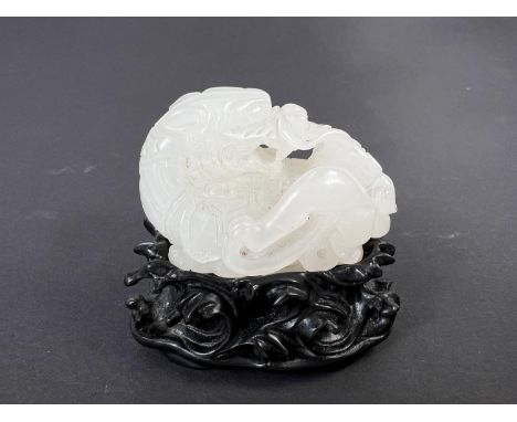 A Chinese carved jade group depicting dragon tortoise fighting a dragon on pierced and carved hardwood stand, length 5cm.