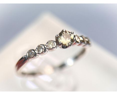 An 18 carat hallmarked white gold ring set with a central clear stone, 23 small diamonds to each shoulder, 2.2gm, size 'O'