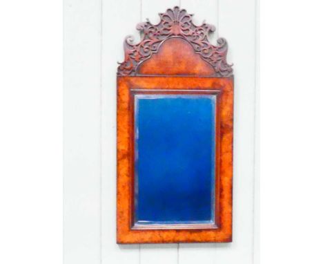 An early to mid twentieth century walnut wall mirror, possibly Waring and Gillow, with blind fretwork cartouche and bevelled 