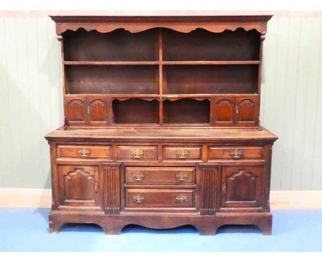 A George III and later oak dresser, the later plate rack with twin cupboards to each side surmounts an architectural base wit