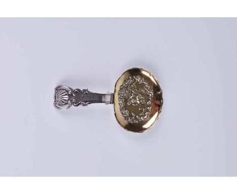 A George III silver caddy spoon with repousse figural scene to the gilt bowl and rococo handle marked T.M.W., Birmingham 1817