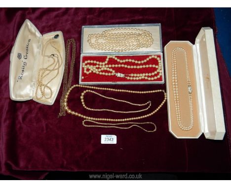 A quantity of boxed faux pearl necklaces, one having long yellow metal chain a/f., boxed Lotus two string faux pearl necklace