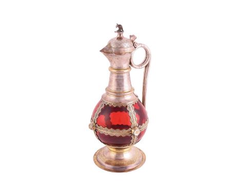 A Victorian silver-mounted ruby glass communion wine jug. The bulbous plain glass body overlaid with parcel gilt mounts; the 