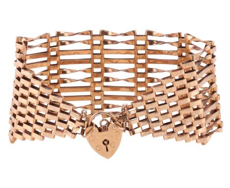 A wide gate bracelet in 9ct yellow gold, with twisted details and completing with a heart-shaped padlock clasp, struck with B