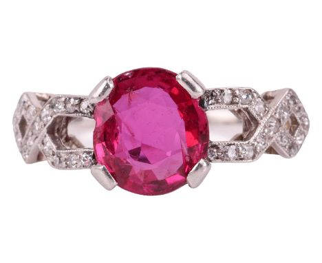 An Edwardian ruby and diamond dress ring, centred with an oval-cut ruby of 8.0 x 7.2 x 3.2 mm, claw-set between geometric ope