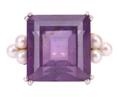 An amethyst and seed pearl dress ring, featuring a step-cut amethyst of 14.0 x 13.2 mm, flanked by trefoil shoulders formed f