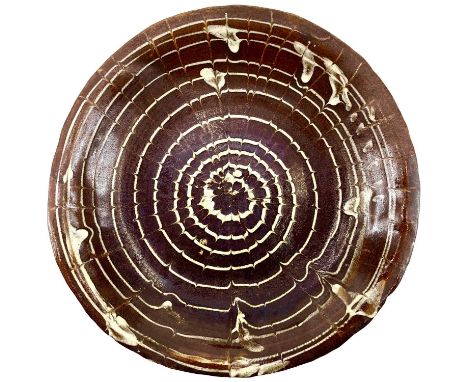A 19th century circular slipware dish with spiral comb decoration. Diameter 28cmThere is a chip on the rim and some discolour