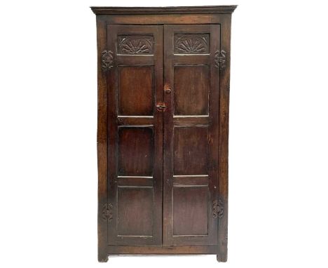 A late 19th or early 20th century oak wardrobe with parts constructed from earlier elements. The twin doors open to reveal a 