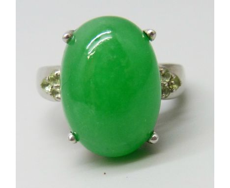A silver ring set with an 11ct green jade central stone with peridot set shoulders, O