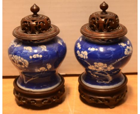 A pair of 19th century Chinese baluster-form ceramic urns decorated with prunus in blue-over-white, with four character marks